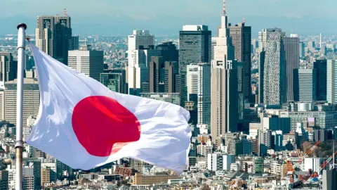 Japanese flag flies in front of the Tokyo skyline