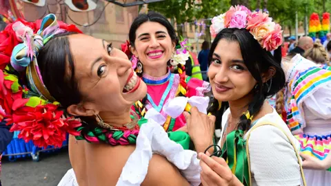 Three women smiling at camera wearing colourful clothes